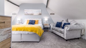 Une chambre à coucher avec un lit, des tables de chevet, un canapé et un tableau au mur.