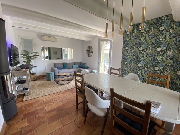 A modern living room with a sofa, dining table, chairs, and a TV.