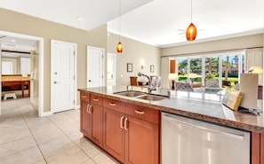 A modern kitchen with a granite countertop, stainless steel appliances, and wooden cabinets.