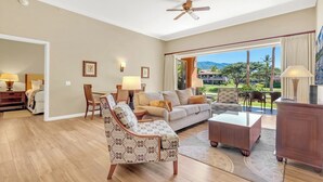 Un salón amplio con sofá, sillones, una mesa de centro y vistas a un paisaje tropical a través de grandes ventanales.