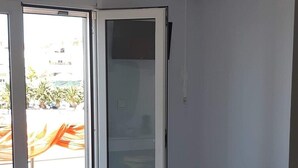 A bedroom with a bed, a sliding glass door leading to a balcony, and an air conditioning unit on the wall. - Ilio Socrates Triple room with sea view. (Thassos)