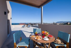 Enjoy a meal on the outdoor terrace with a view of the sea and distant hills.