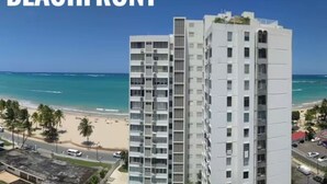 Ein Hochhaus mit Blick auf den Strand, ausgestattet mit mehreren Balkonen und einem strahlend blauen Himmel.
