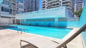 Ein Pool mit Liegestühlen, umgeben von hohen Gebäuden.
