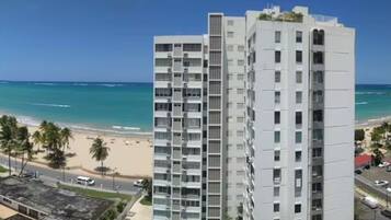 Ein Hochhaus mit Blick auf den Strand, ausgestattet mit mehreren Balkonen und einem strahlend blauen Himmel.