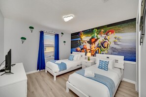 A bedroom with two beds, a desk, a TV, and a large mural on the wall. - Beautiful Contemporary Decor With Themed Rooms, Game Room and Theater (Kissimmee)