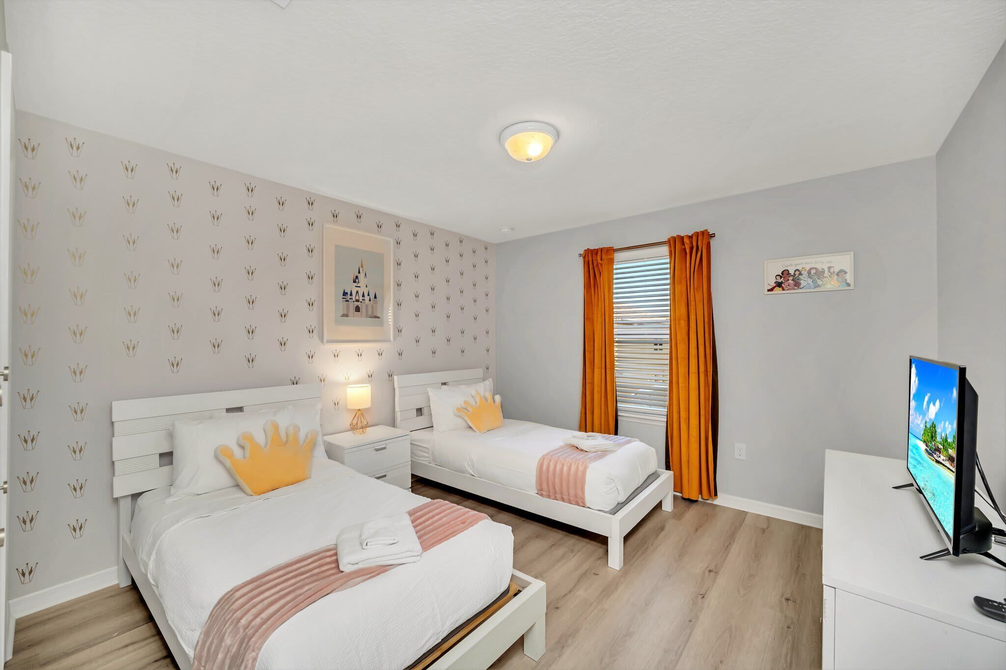 Een hotelkamer met twee bedden, een televisie en een raam met gordijnen.