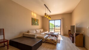 Ein modernes Wohnzimmer mit einer Couch, Hocker und einem Fernseher.