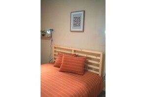 Cozy retreat with a bed, framed quote, and potted plant.