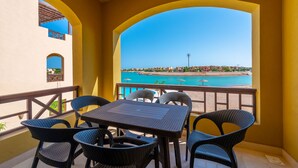 A balcony with a table and chairs, overlooking a beach and pool area. - Vesta - Luxury APT - 1BR - Sabina (El Gouna)