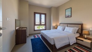 A bedroom with a bed, bedside tables, a TV, a window, and a painting on the wall. - Vesta - Luxury APT - 1BR - Sabina (El Gouna)