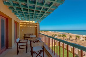 Ein Balkon mit Blick auf den Strand, Holzmöbel und eine Decke mit hängenden Körben.