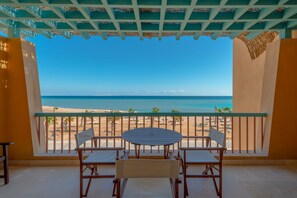 Ein Balkon mit Tisch und Stühlen mit Blick auf einen Strand.