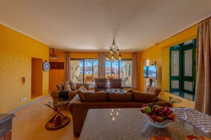 Una sala de estar con un sofá, una mesa de centro de vidrio y un frutero.