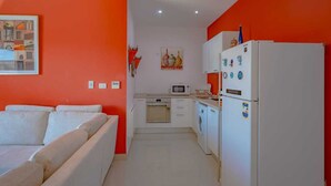 A compact kitchen with white appliances, a microwave, and a washing machine.