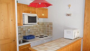Cocina compacta con armarios de madera, microondas, estufa y un lavamanos pequeño.
