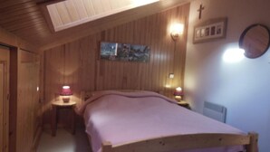 A cozy bedroom with a wooden bed, a small bedside table with a lamp, and a wall-mounted light fixture. - 250m from resort center, 1st floor, balcony, tv, ski locker, 40m², Champagny-en-Vanoise (Champagny-en-Vanoise)