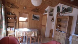 A cozy dining area with a round table and chairs, wooden cabinets, and a bookshelf. - 250m from resort center, 1st floor, balcony, tv, ski locker, 40m², Champagny-en-Vanoise (Champagny-en-Vanoise)