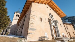 A historic church with a bell tower, stone steps leading to the entrance, and a bench outside. - 250m from resort center, 1st floor, balcony, tv, ski locker, 40m², Champagny-en-Vanoise (Champagny-en-Vanoise)