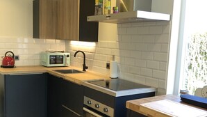 A modern kitchen with a wooden countertop, a built-in oven, a microwave, and a stainless steel range hood. - RENOVATED vacation home by the sea Breskens10 pers. child friendly, dog welcome.  (Breskens)