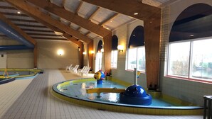 An indoor swimming pool with a central water feature, surrounded by white chairs and a tiled floor. - RENOVATED vacation home by the sea Breskens10 pers. child friendly, dog welcome.  (Breskens)