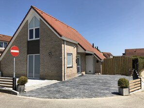 Een huis met twee verdiepingen, een dak met rode tegels, een verbodsbord en een geplaveid oprit.