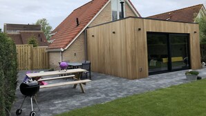 A modern house with a sloped roof, a wooden exterior, and a large sliding glass door. - RENOVATED vacation home by the sea Breskens10 pers. child friendly, dog welcome.  (Breskens)