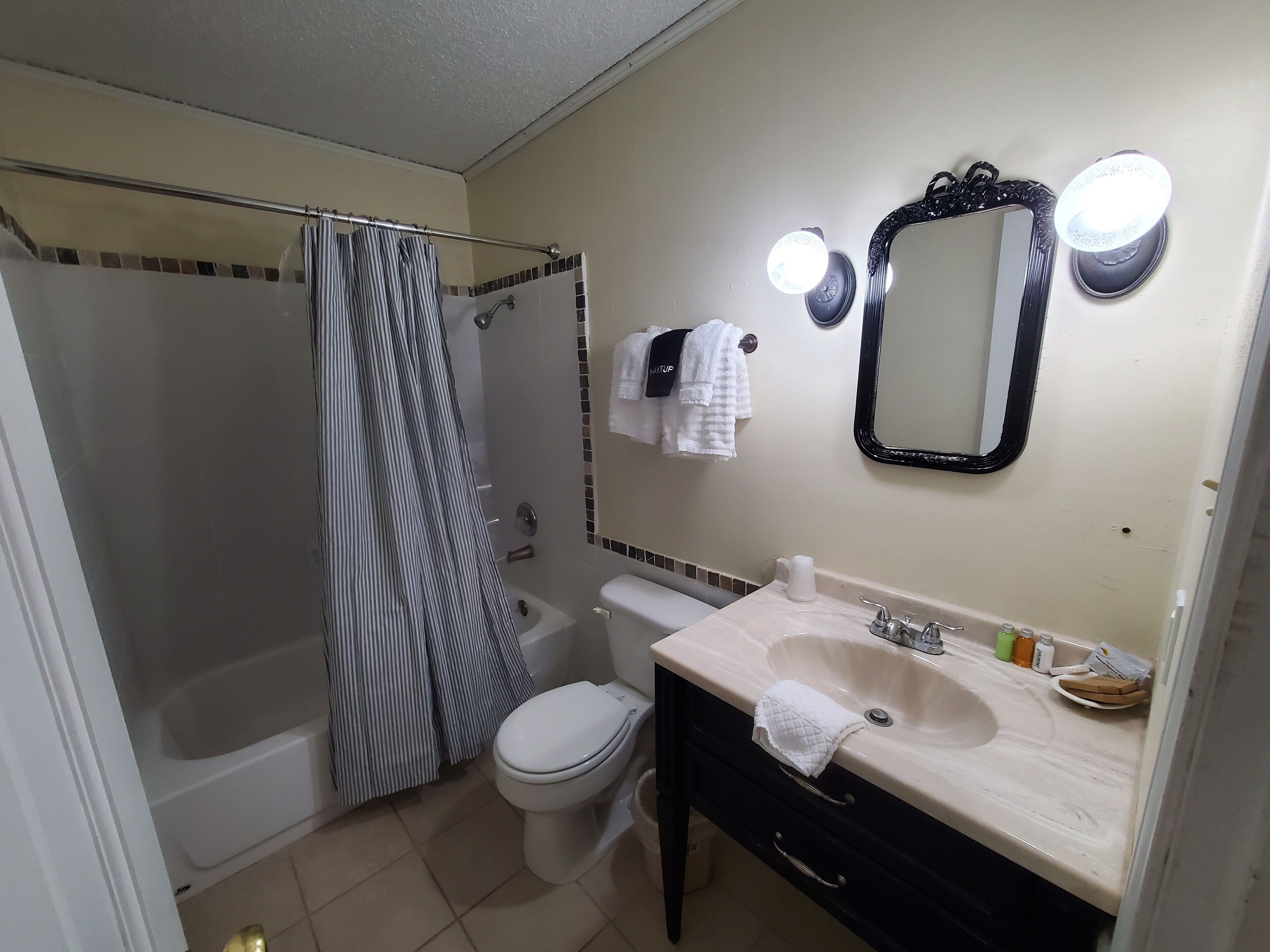 Un bagno con vasca, WC, lavandino e uno specchio illuminato.