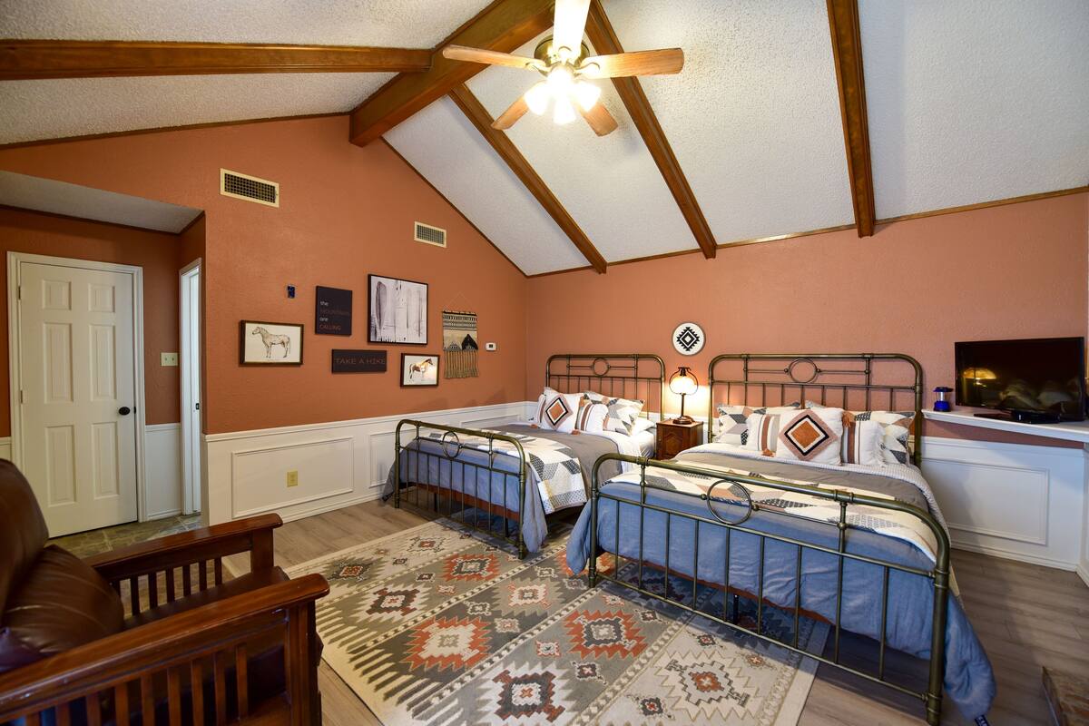 A bedroom with two beds, a ceiling fan, and a patterned rug.