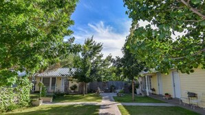 A residential area with a paved pathway leading to a house with a metal roof. - Butterfield Inn Main Street Cottages (Fort Davis)