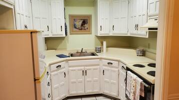 A kitchen with white cabinets, a sink, a stove, and a refrigerator.