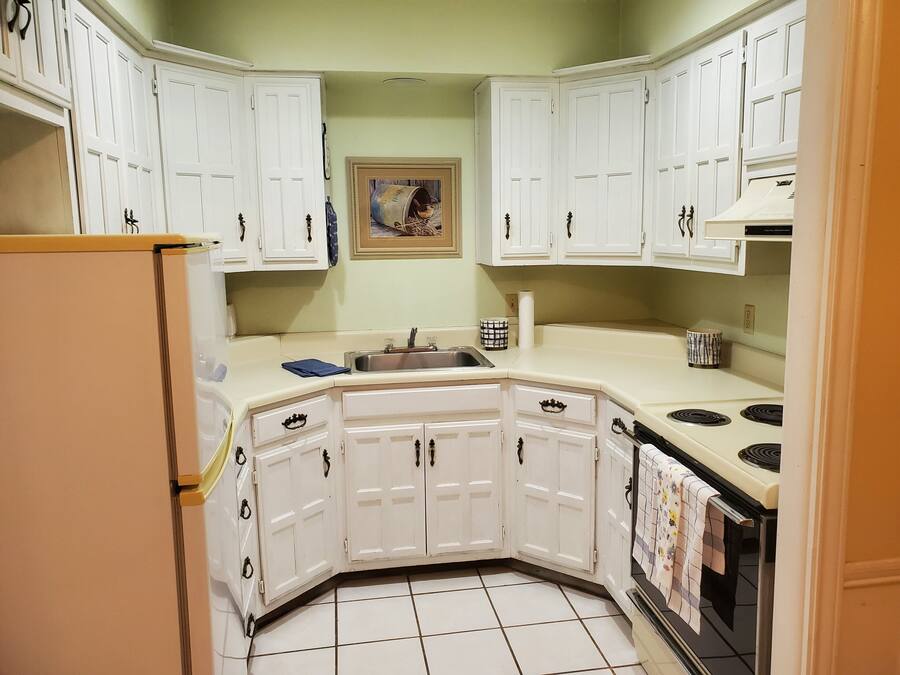 A kitchen with white cabinets, a sink, a stove, and a refrigerator.