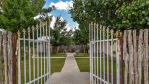 A gated entrance with a concrete path leading to a house. - Butterfield Inn Main Street Cottages (Fort Davis)