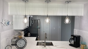 A modern kitchen with a white countertop, stainless steel appliances, and pendant lighting. - Oceanview Beach Getaway, Great balcony!! (Galveston)