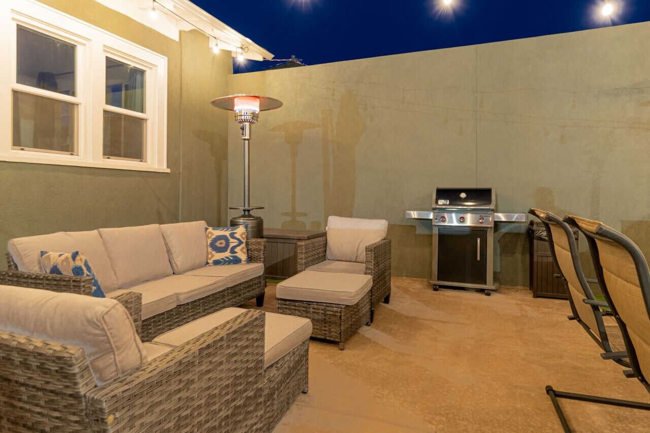 An outdoor patio with wicker furniture, a grill, and a patio heater.