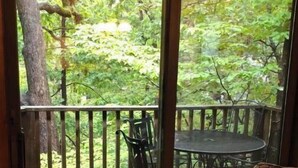 Une pièce dotée d’une porte-fenêtre coulissante donnant sur une terrasse extérieure avec une table et des chaises.