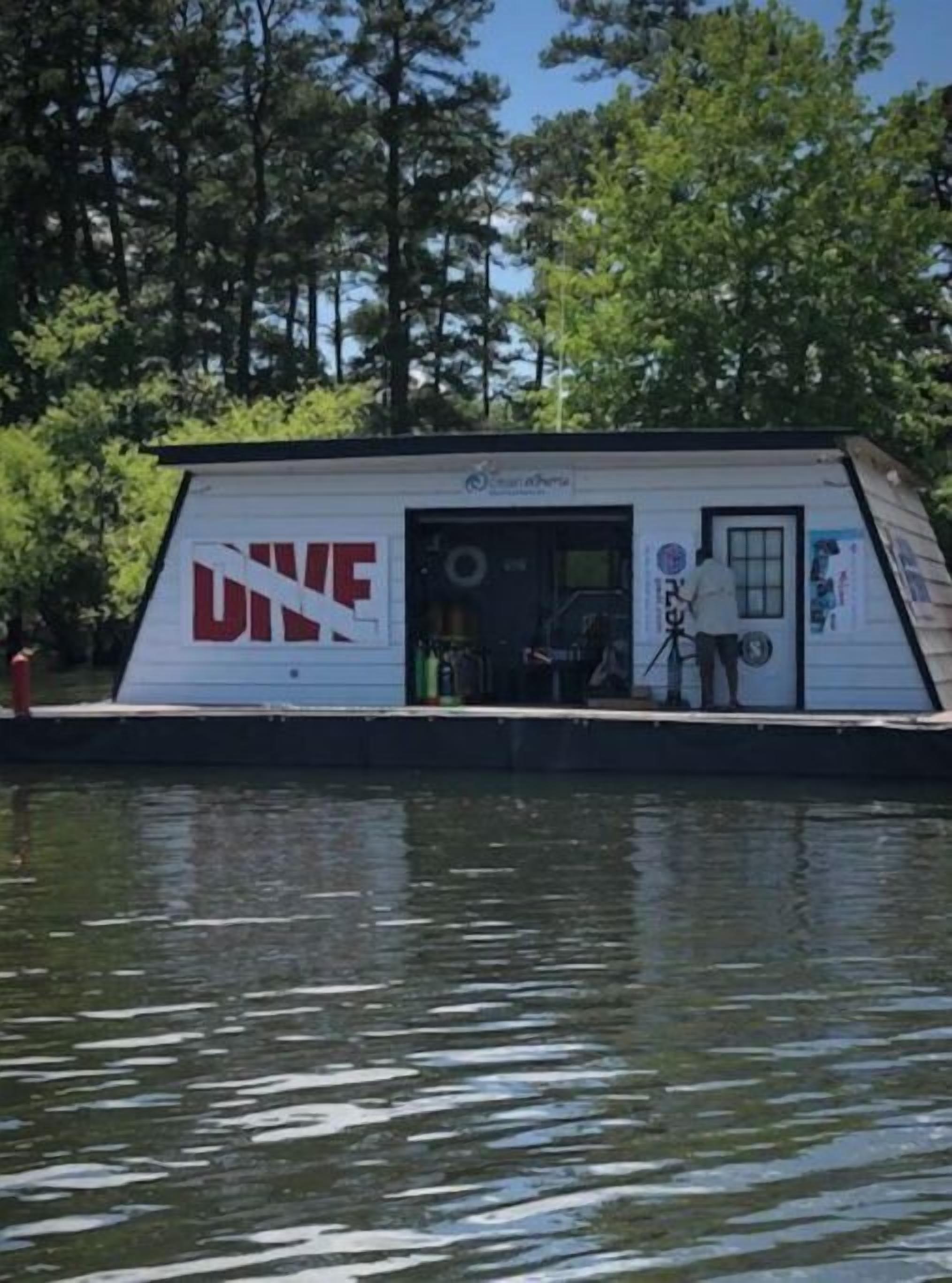 Un petit bateau à un seul étage, sur lequel on peut lire l’inscription « PLONGÉE », avec une porte et une petite fenêtre.