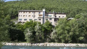 A multi-story hotel with balconies, situated by a river with a stone embankment. - Hostal Rio Ara Bellosta (Fiscal)