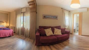 A room with a bed, a sofa, a TV, and a wooden floor.