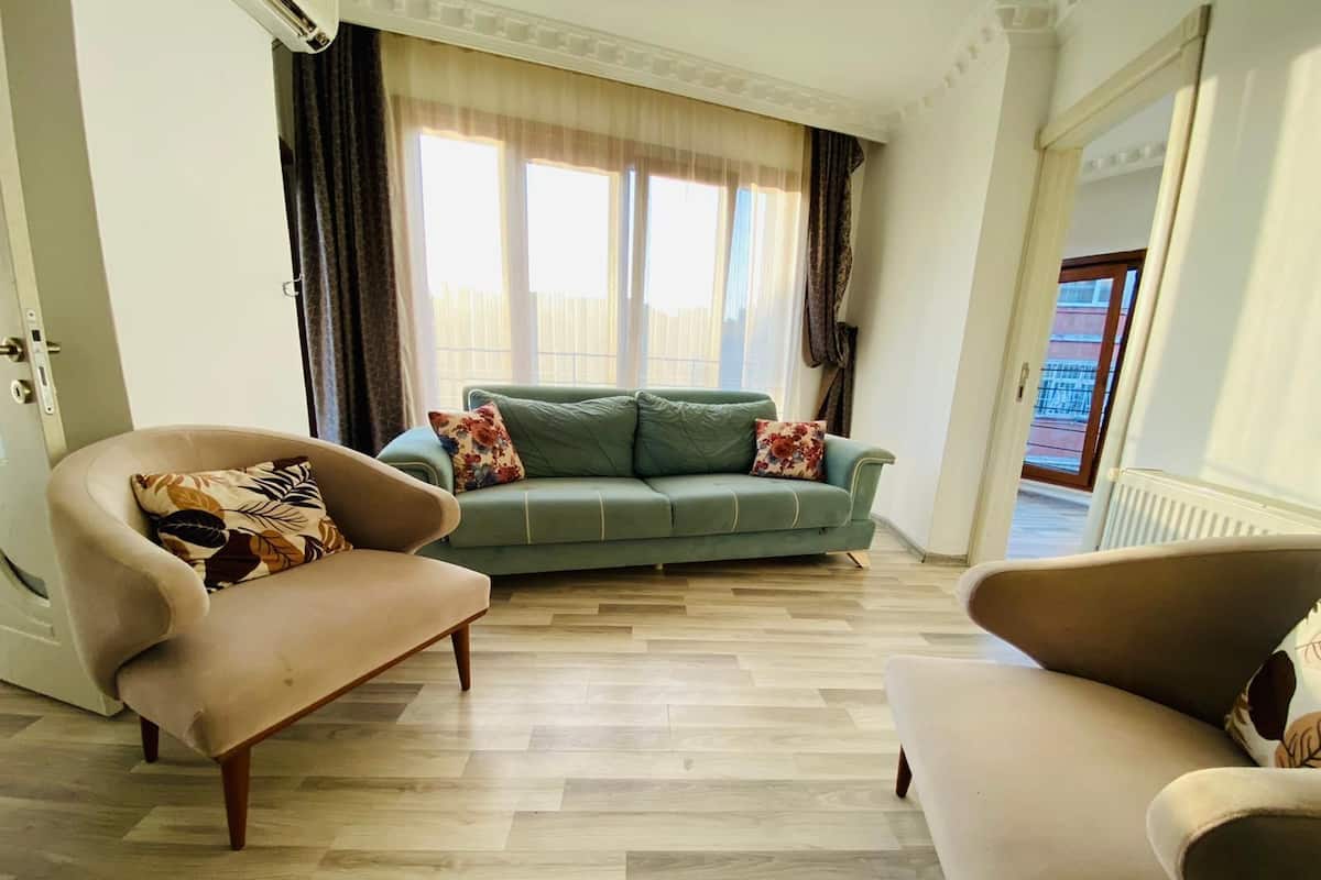 A living room with a green sofa, two armchairs, and patterned cushions.