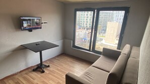 A room with a wooden floor, a black table, a beige sofa, and a TV mounted on the wall. - Dolapdere Zona Apart (Istanbul)