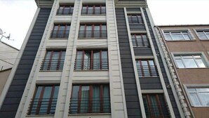 A multi-story building with a symmetrical facade, featuring evenly spaced windows with red frames and white trim. - Dolapdere Zona Apart (Istanbul)