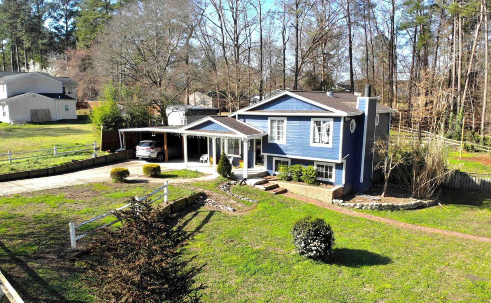 Une maison à deux étages avec un garage, une véranda et une pelouse bien entretenue.