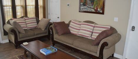 A living room with two sofas, a coffee table, and a painting on the wall.