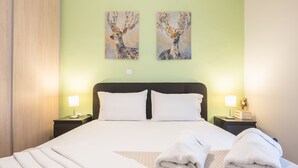 A hotel room with a large bed, two nightstands, two wall-mounted lamps, and two paintings of deer.