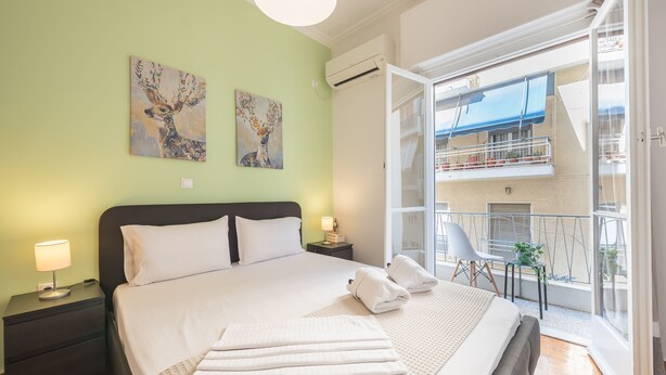 A bedroom with a bed, nightstands, and a balcony with a view.