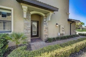 Stunning residential building with a stone facade, symmetrical entrance, and lush garden area.