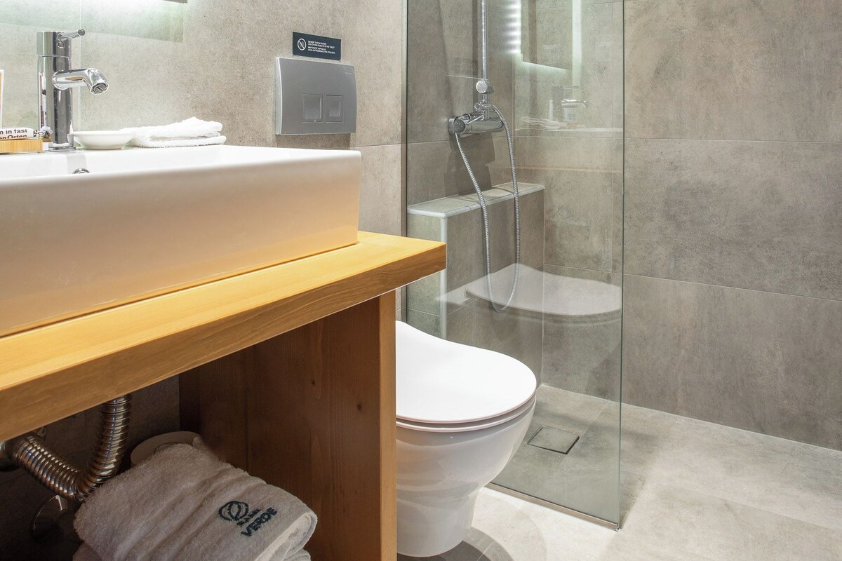 A modern bathroom with a glass-enclosed shower, a wooden vanity with a sink, and a toilet.