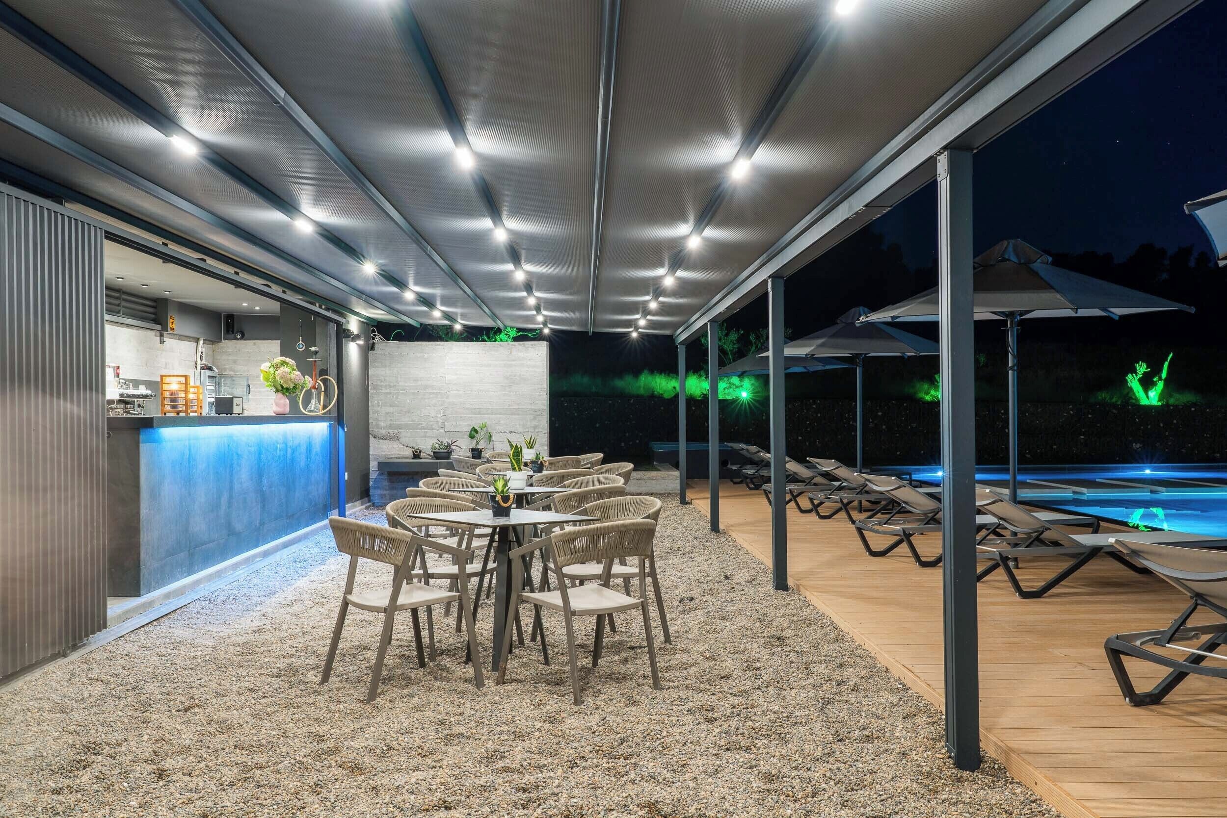 An outdoor patio area with a bar, seating, and a pool.