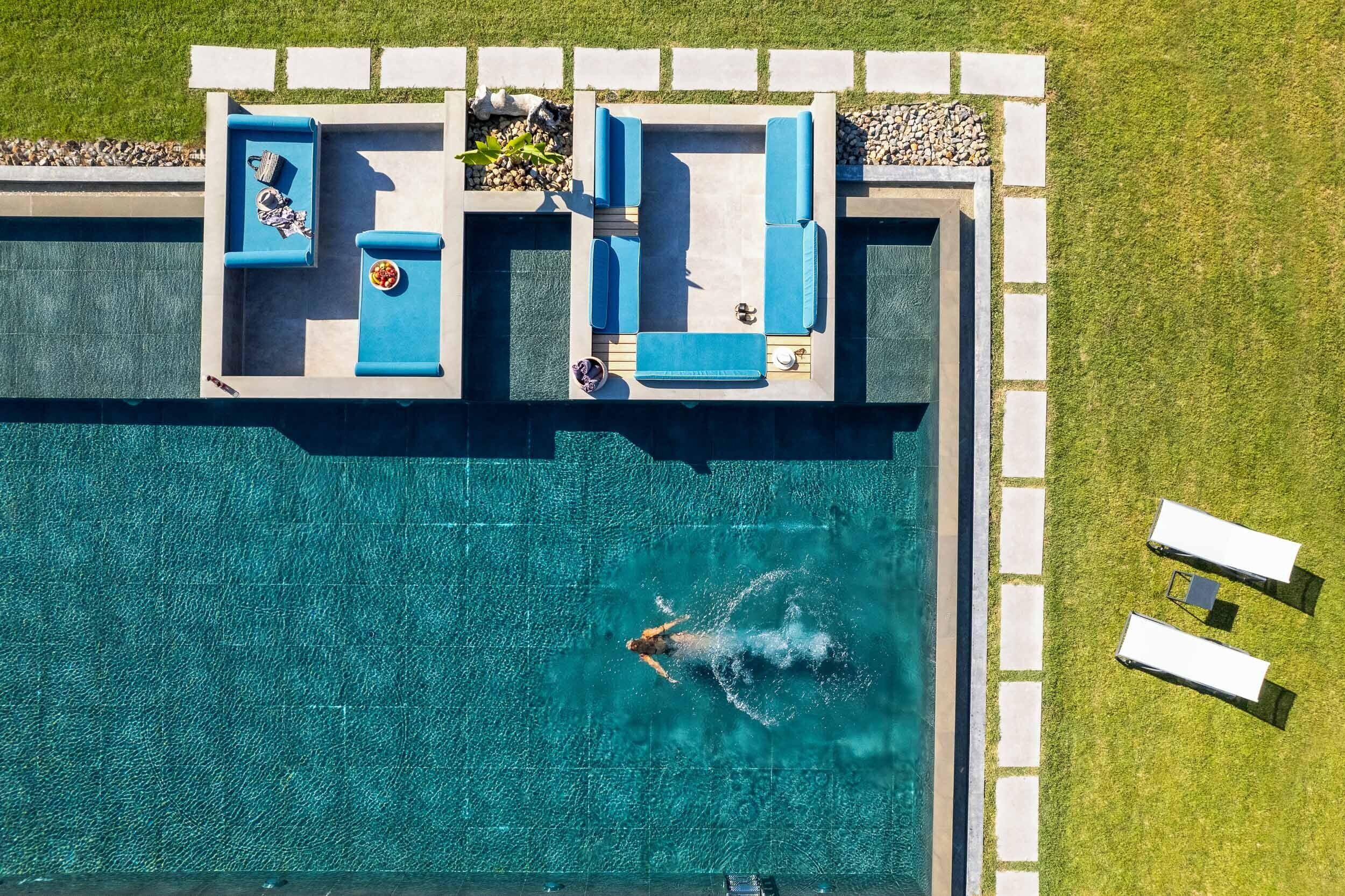 An aerial view of a swimming pool with a hot tub and lounge chairs.